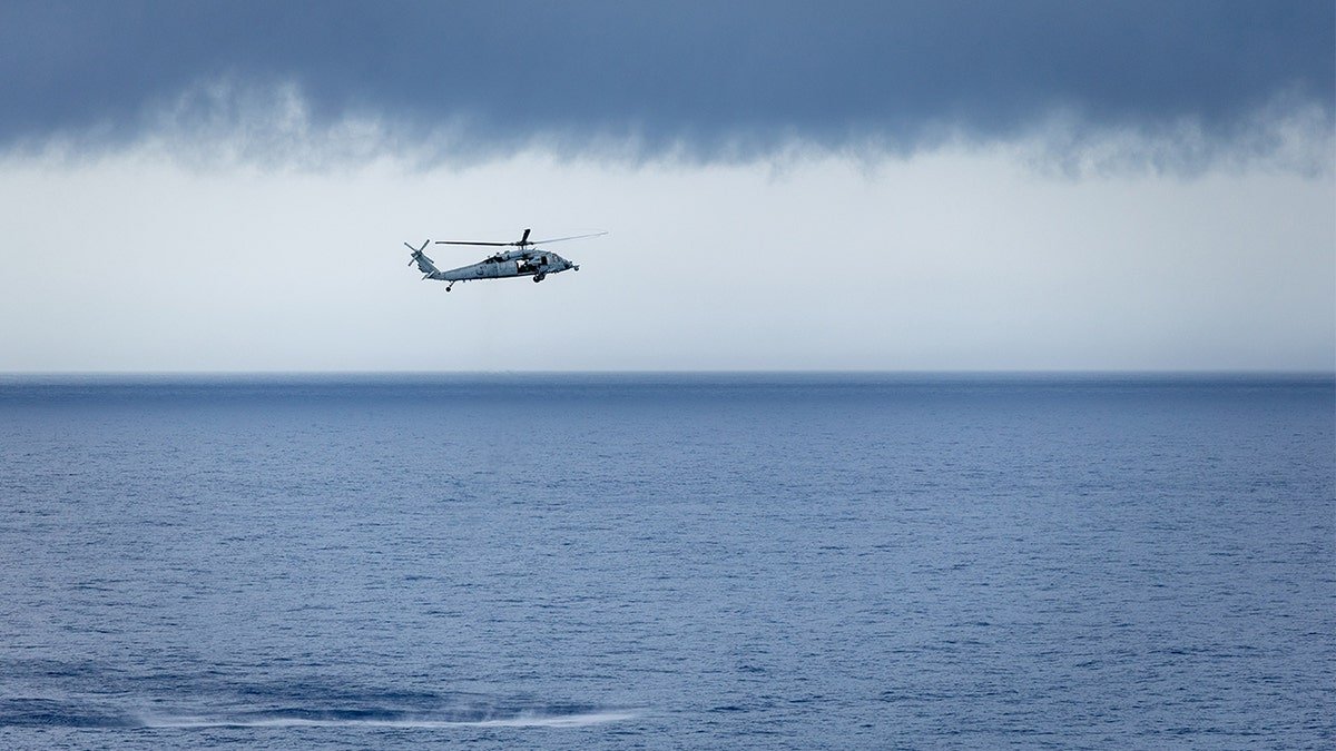 US Navy helicopter flies above ocean