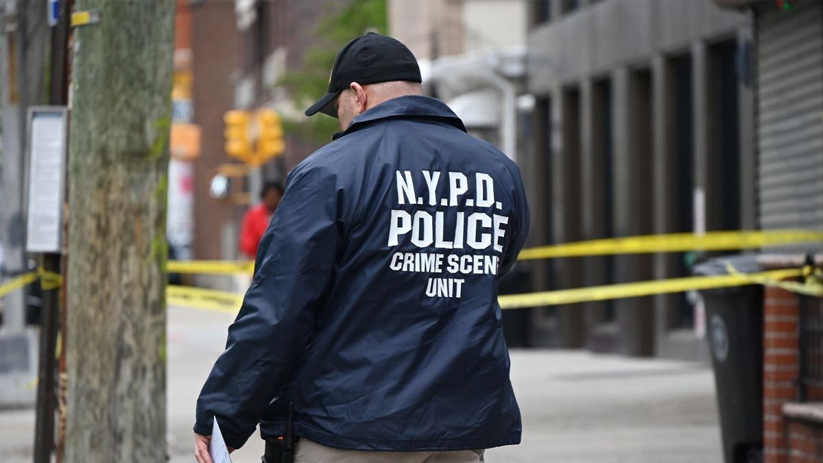 nypd officer walks through a crime scene