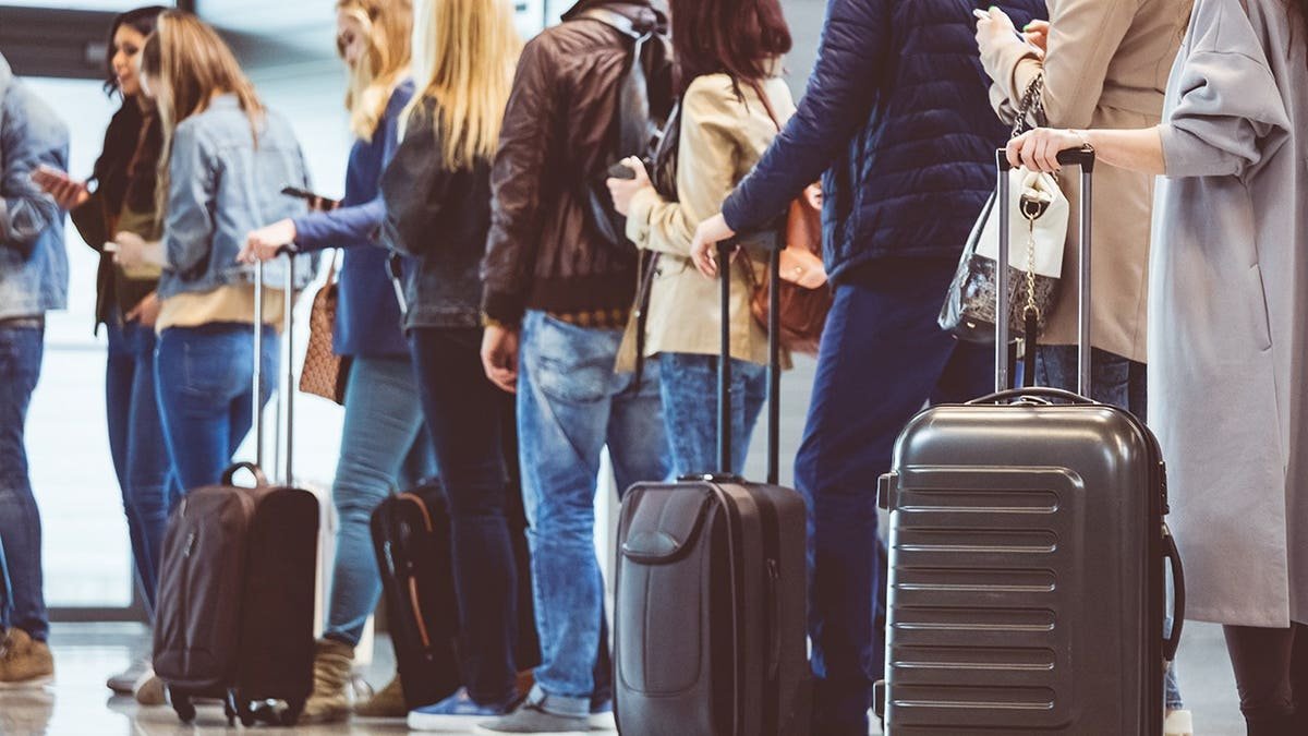 Passengers standing in a queue at an airport boarding gate.