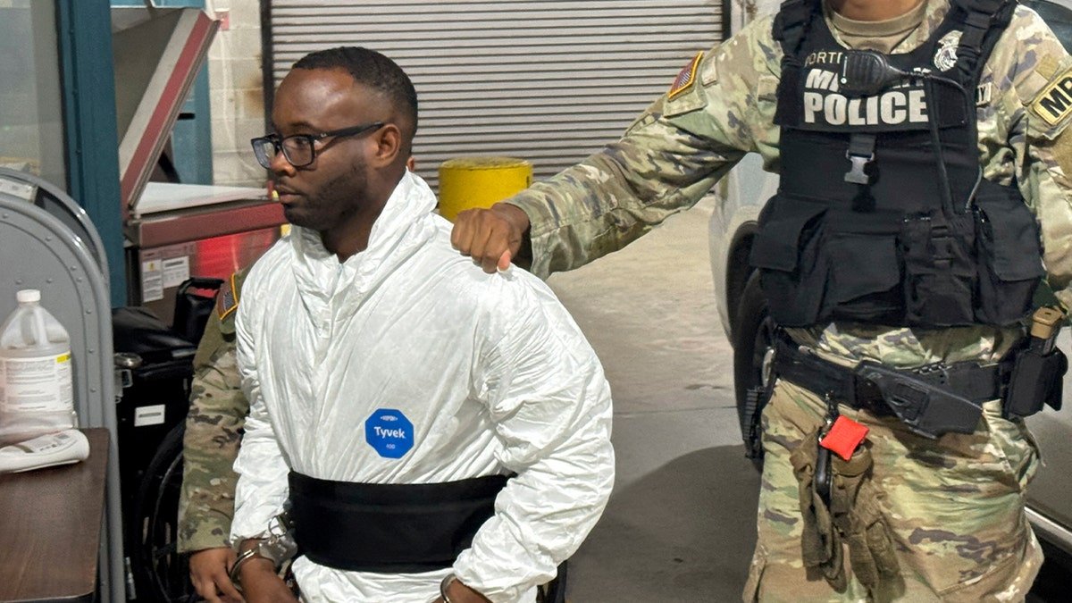 Sgt. Quornelius Radford escorted by military police into a booking room at Liberty County Jail