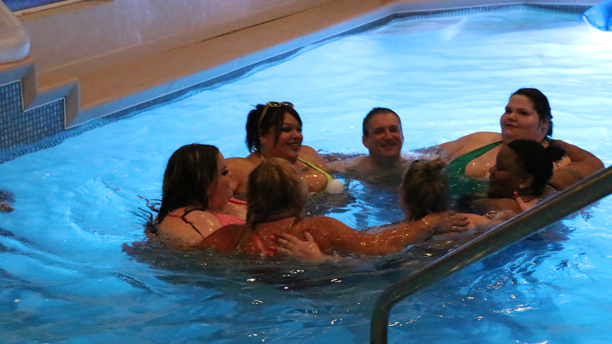 Pearadise founder Stefan Wilhelmy stands in a swimming pool with members of the Pearadise community in Las Vegas