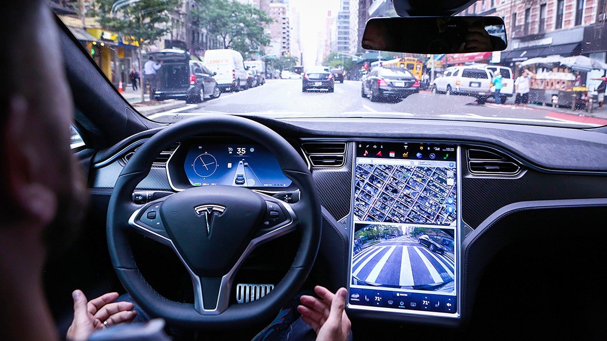 Tesla vehicle stopped at a traffic light on a city street