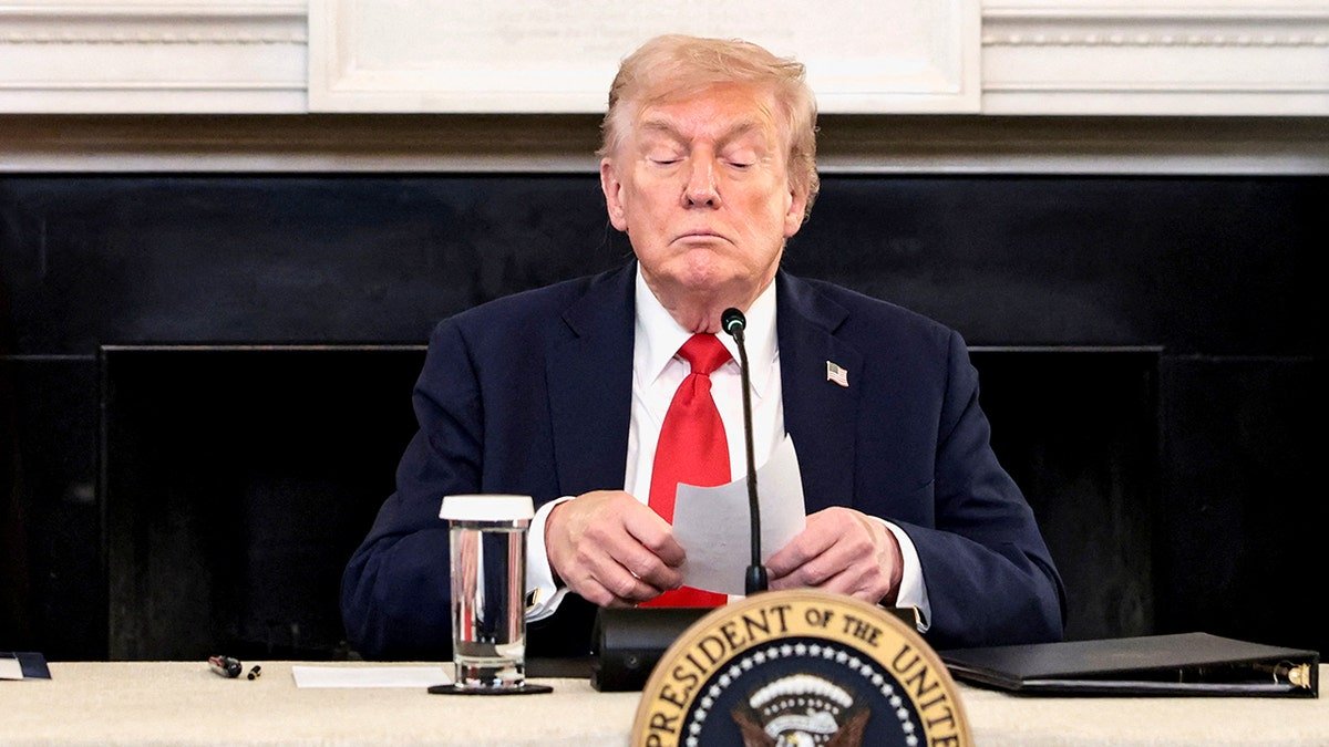 President Donald Trump holding a note handed by Secretary of State Marco Rubio at the White House