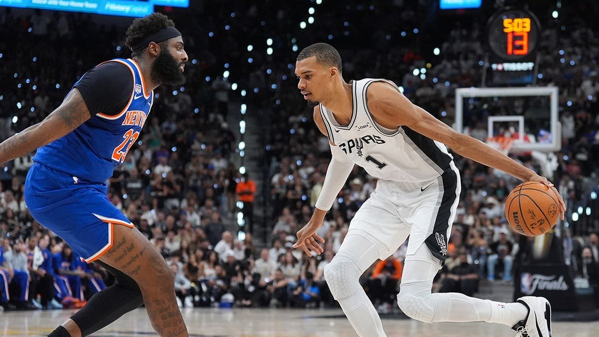 Victor Wembanyama driving with basketball as Mitchell Robinson defends in NBA Finals game