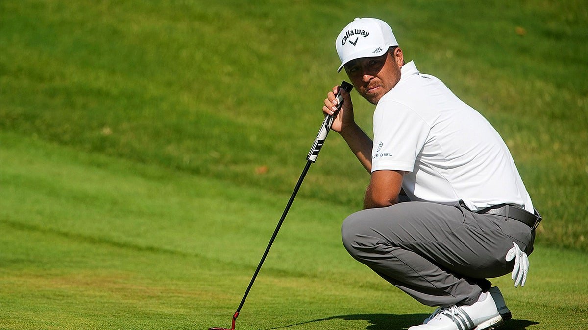 Xander Schauffele looking toward Aldrich Potgieter chipping onto the green at the ninth hole.