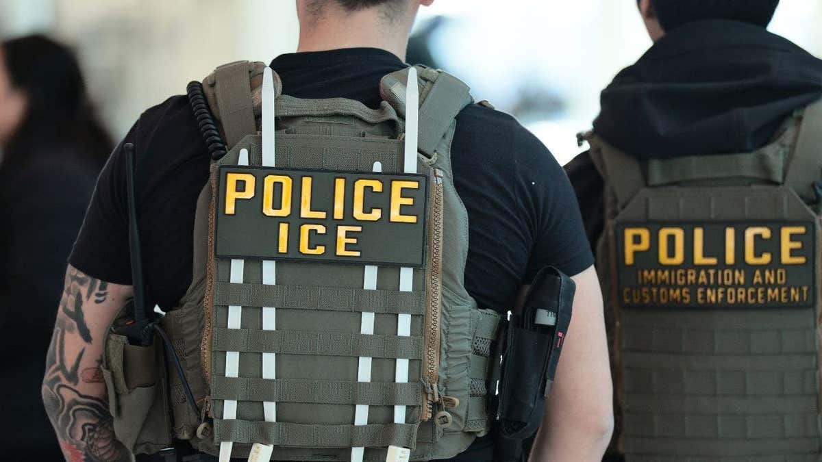 Backs of Immigration and Customs Enforcement agents as they walk