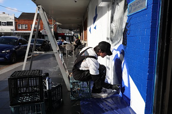 Artist Sid Tapia working on a mural of legendary Canterbury Bulldogs player Terry lamb, outside Jobel’s Cafe.