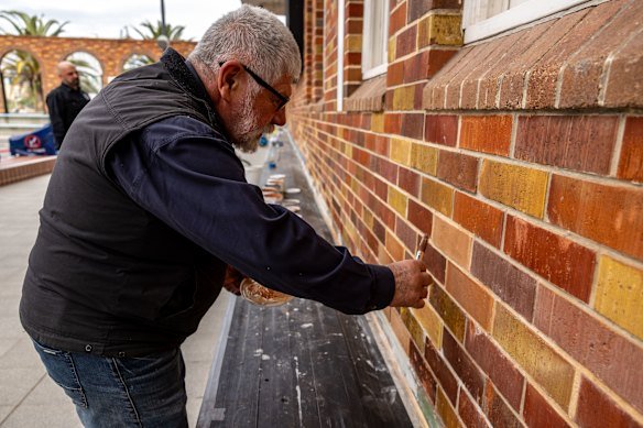 Stonemason Kris Karwczyk is among workers who have painted thousands of bricks in shades of red, rust, yellow and green to match the original brickwork.