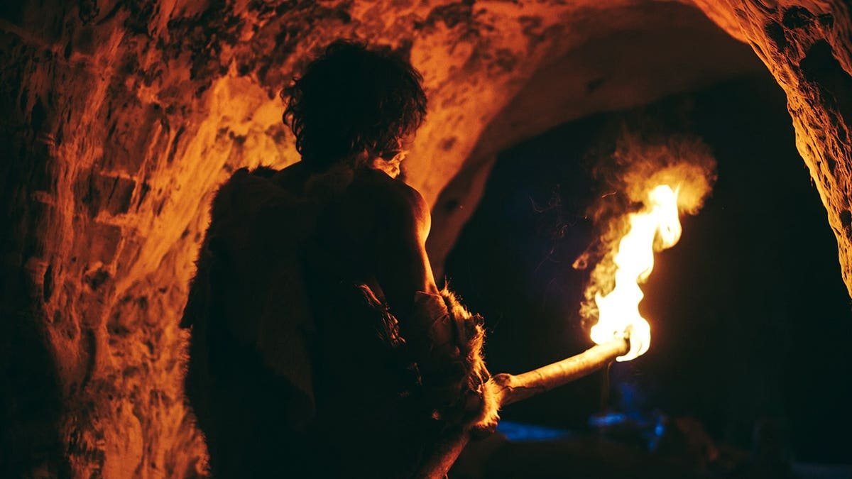 Stock image of caveman holding fire stick