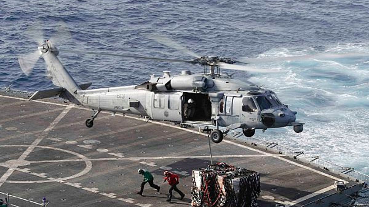 FILE - In this May 19, 2019 photo, an MH-60S Sea Hawk helicopter transports cargo from the fast combat support ship USNS Arctic to the Nimitz-class aircraft carrier USS Abraham Lincoln during a replenishment-at-sea operation in the Arabian Sea.