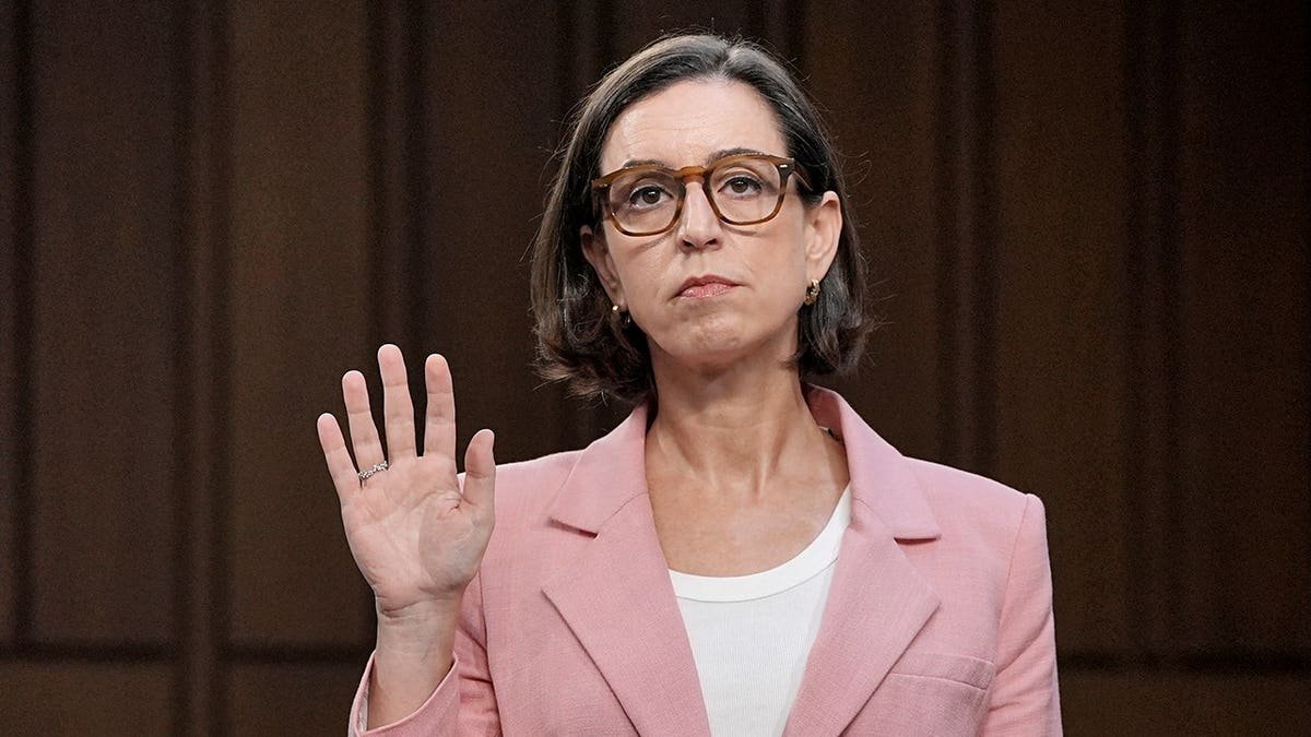 Liz Oyer standing with her right hand raised to take an oath during a Senate hearing.