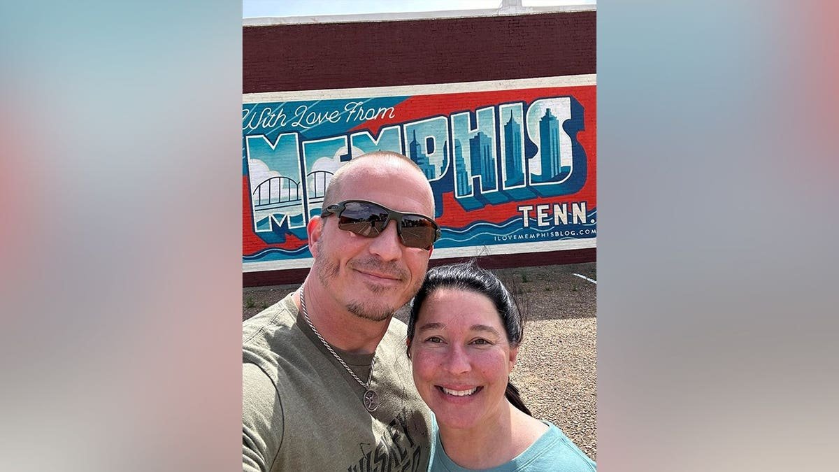 Justin Elrod and Lena Elrod smile for a selfie in front of a colorful
