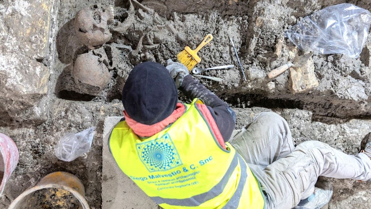 Archaeologist excavating skeleton at church site