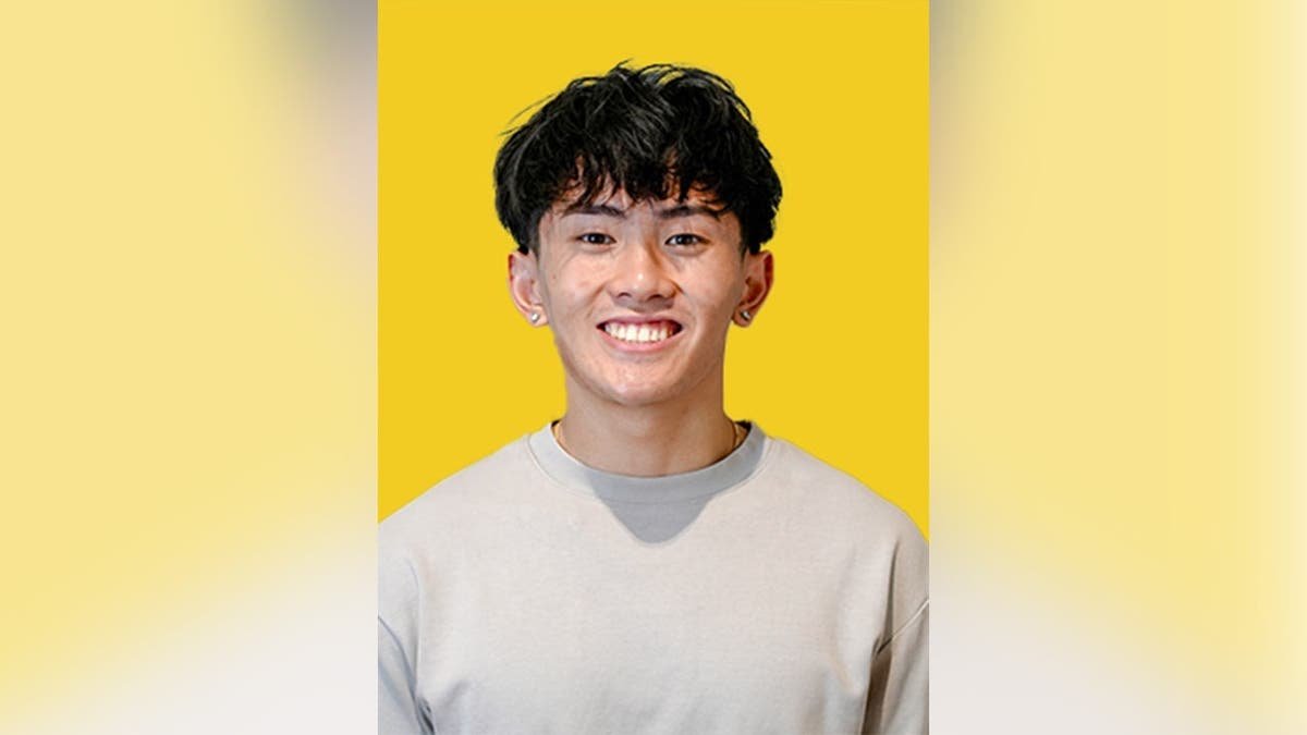 Kenny Truong smiling in front of a yellow background.