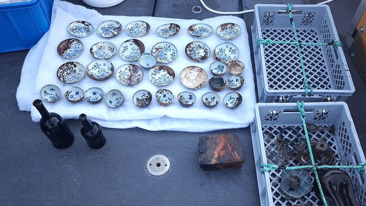 View of porcelain artifacts laid out next to other finds on ship