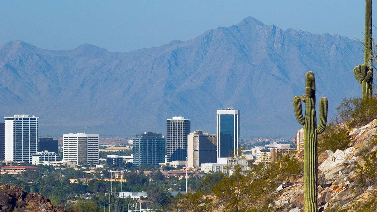 Phoenix skyline with mountains in the background and cactus in the foreground.