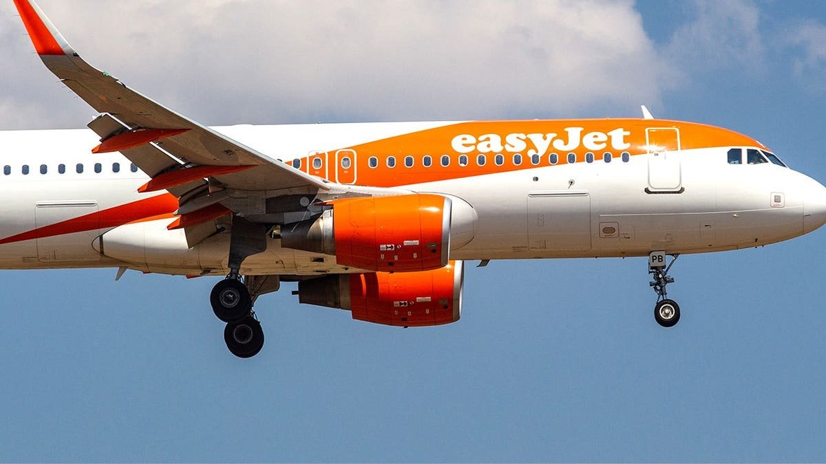 Close-up stock image of orange EasyJet plane in the air