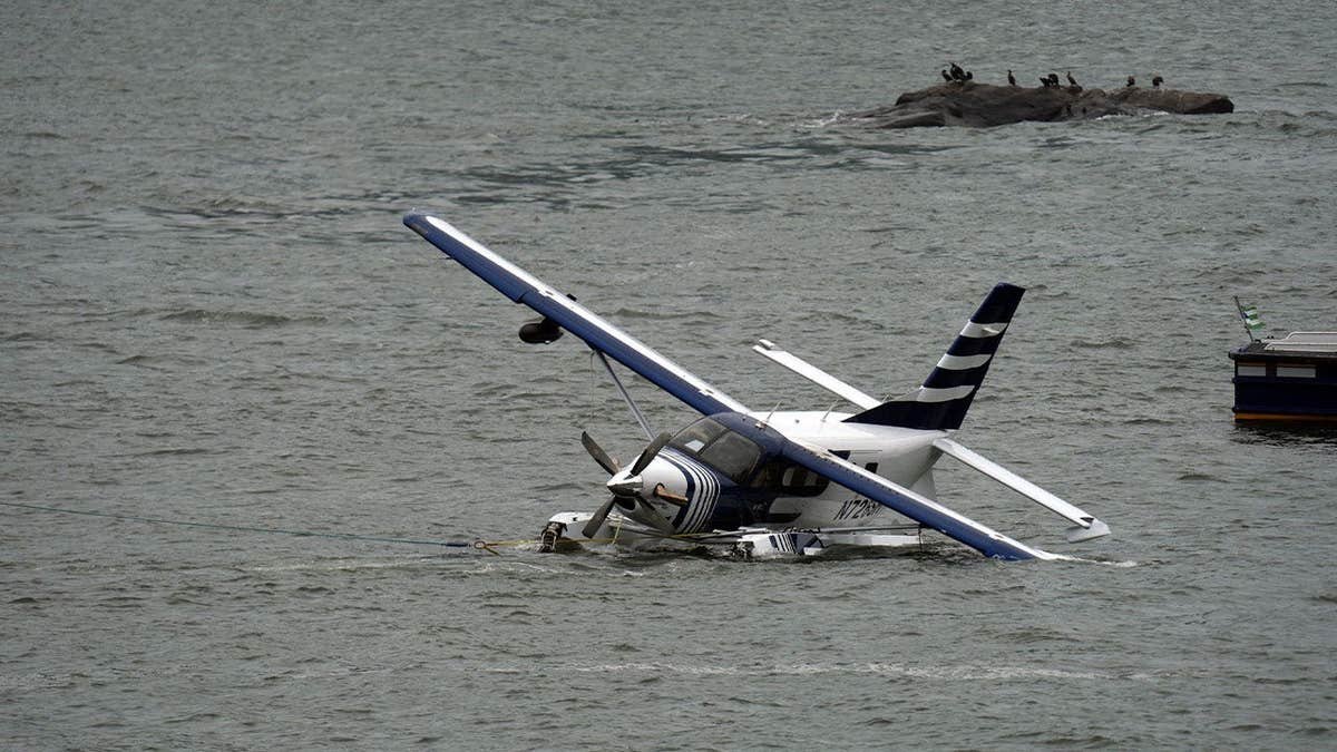 A seaplane sits partially submerged in New York City's East River after a hard landing
