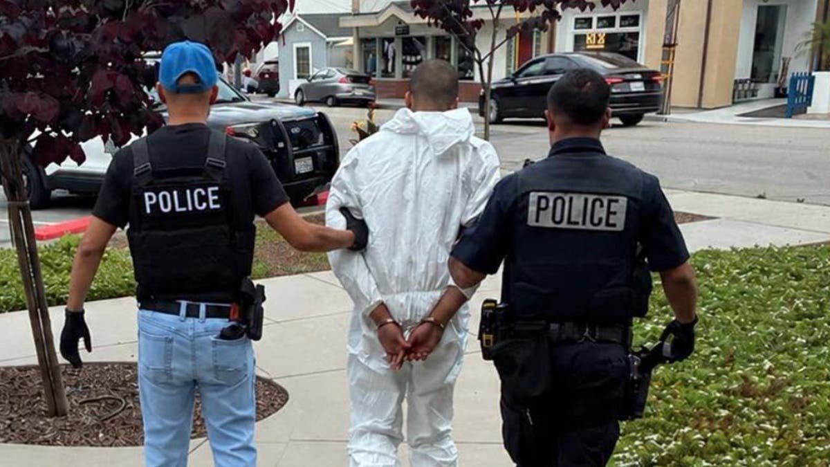 photo shows two police officers escorting Leibelt in handcuffs