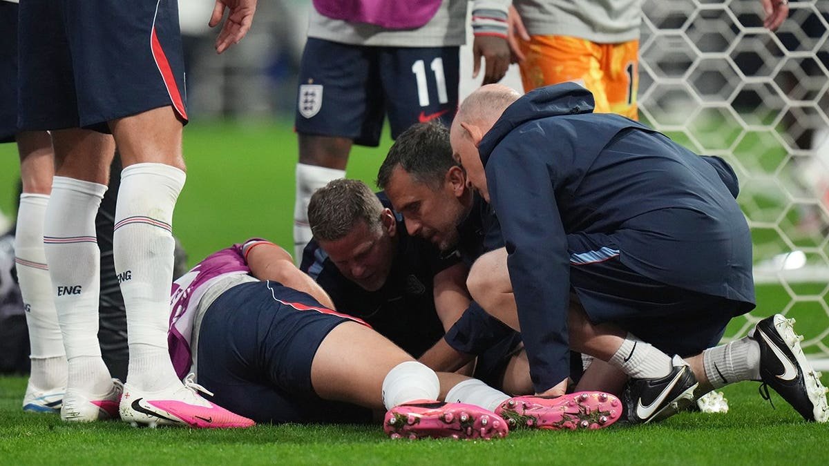 England's Jordan Henderson (14) attended to by training staff after injury during postgame celebration in Mexico City.
