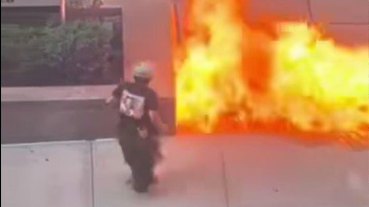 The suspect stands near the flames as they erupt
