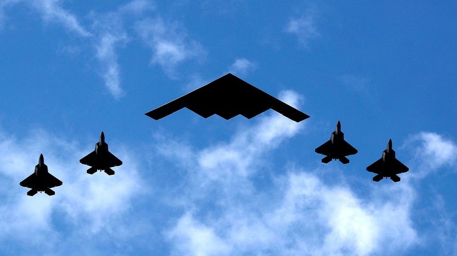 B-2 bomber flanked by F-22 Raptor fighter planes