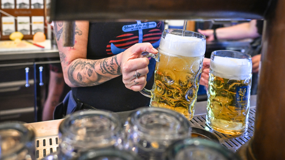 A woman is seen pouring beer from a tap at a bar.