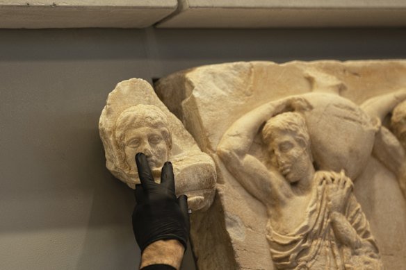 An Acropolis Museum staff member places a male head on a frieze during a ceremony for the repatriation of three sculpture fragments in Athens in 2023.  