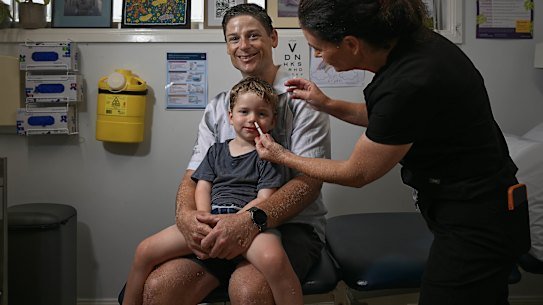 Dr Annalyse Crane giving three-year-old Hamish Gray his first nasal spray flu vaccine at Family Medical Practice in Kirrawee, alongside his father, Ben. 