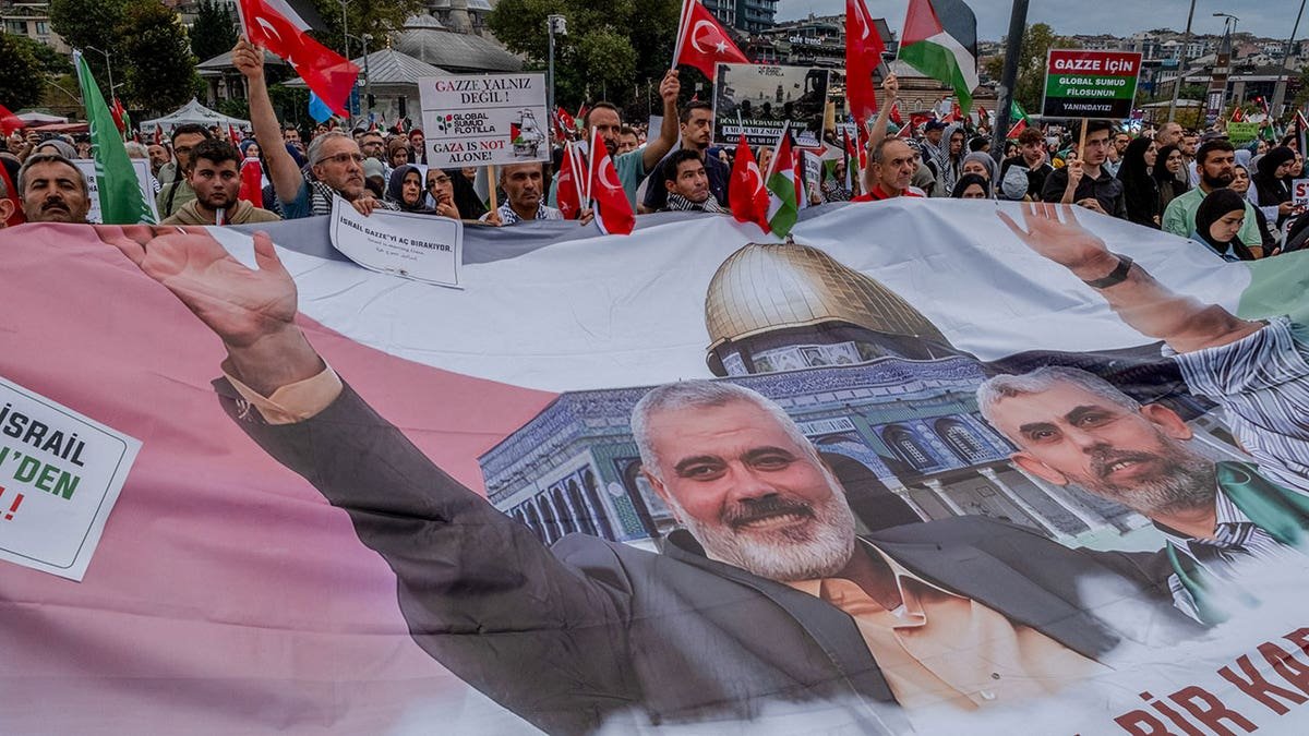 A group of protesters seen carrying a banner with pictures of the slain Hamas leaders Ismail Haniyeh and Yahya Sinwar.