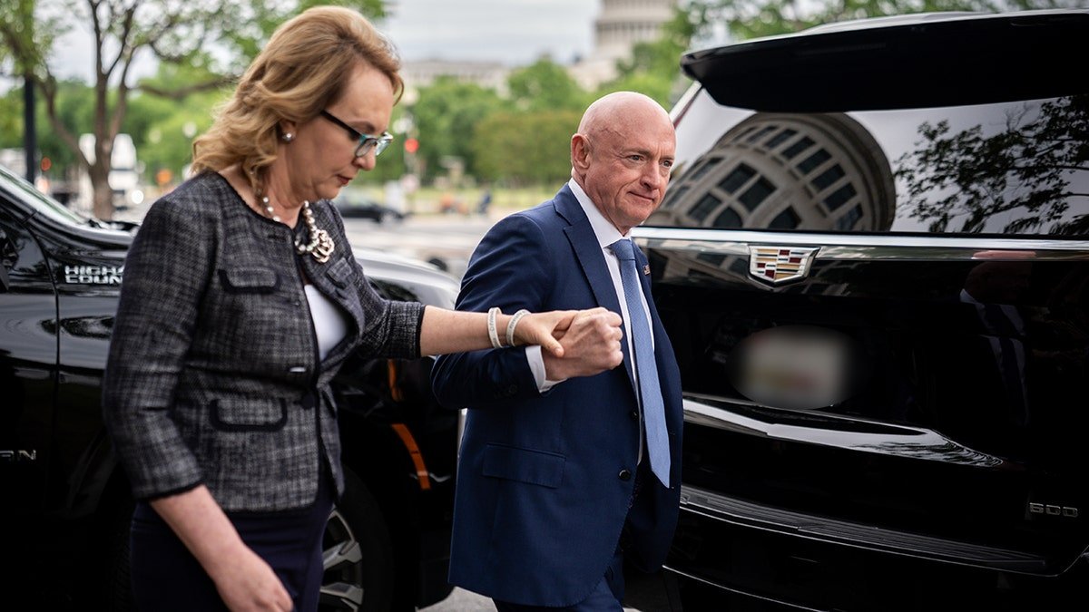 Mark Kelly and Gabby Giffords walk toward a black SUV while holding hands in Washington.