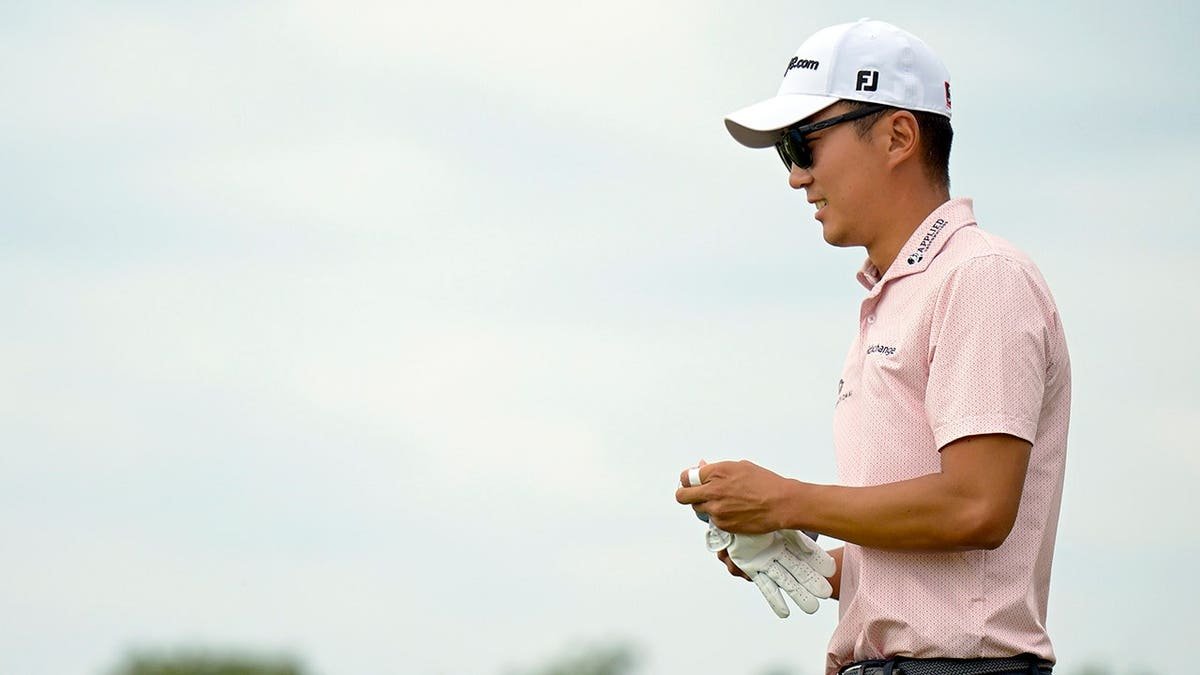 Michael Kim walks to his ball after hitting a tee shot on the golf course.