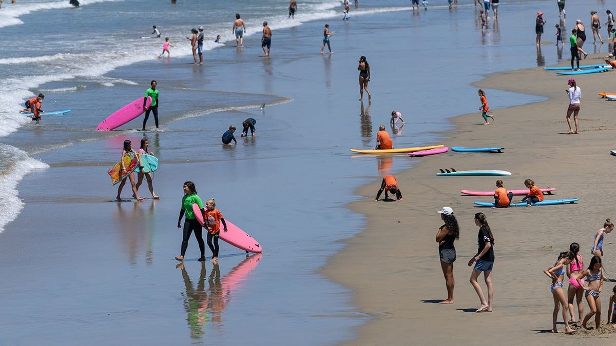 Beachgoers sit and walk on the sand at Newport Beach.