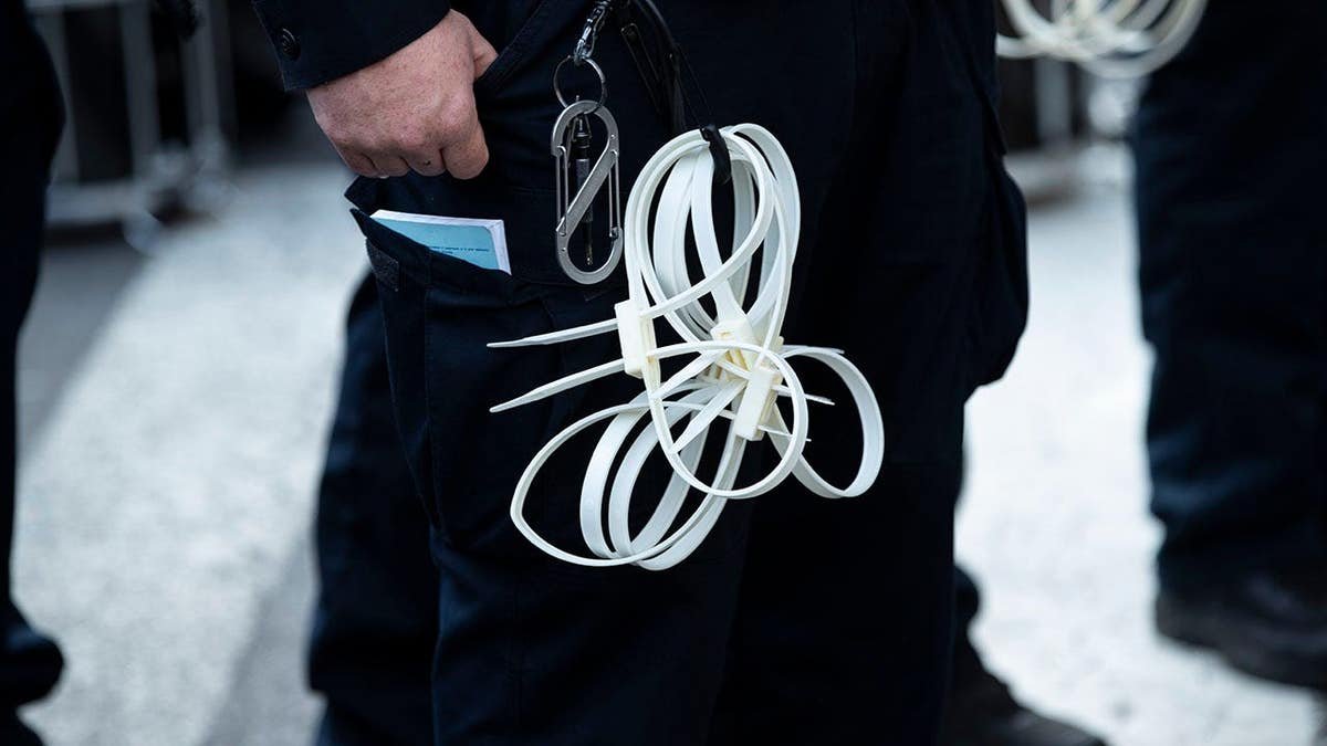 NYPD officers stand with zip tie handcuffs in Manhattan.