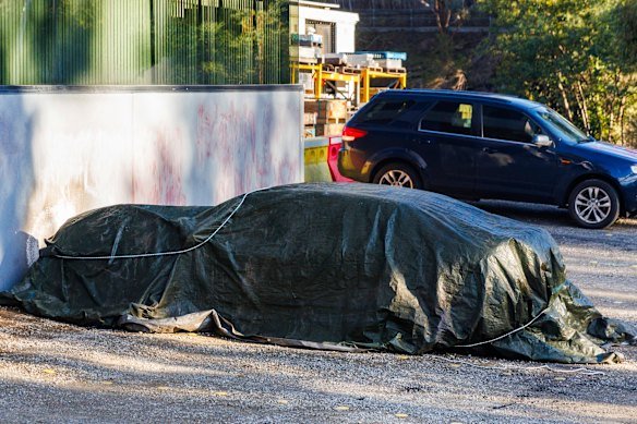 A burnt car was covered by a tarpaulin after the early morning attack at Lovitt Technologies on July 5 last year.