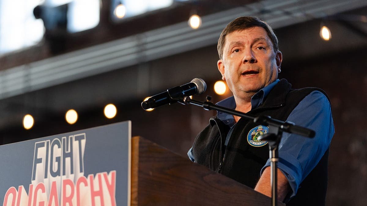 Troy Jackson speaking at a microphone during a political campaign event in Portland, Maine.