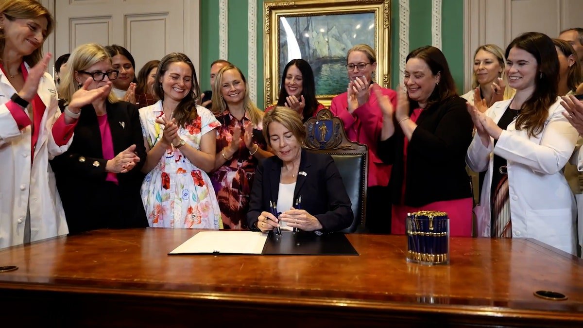 people clap as Gov. Healey signs bill
