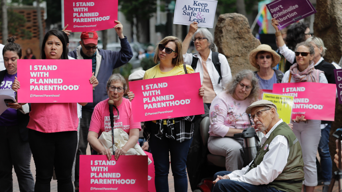 FILE - In this July 10, 2018 file photo, protesters hold signs supporting Planned Parenthood in Seattle, as they demonstrate against President Donald Trump and his choice of federal appeals Judge Brett Kavanaugh as his second nominee to the Supreme Court. On Tuesday, March 5, 2019, the American Medical Association and Planned Parenthood jointly filed a federal court lawsuit challenging a new Trump administration rule for family-planning grants which had been sought by anti-abortion activists.