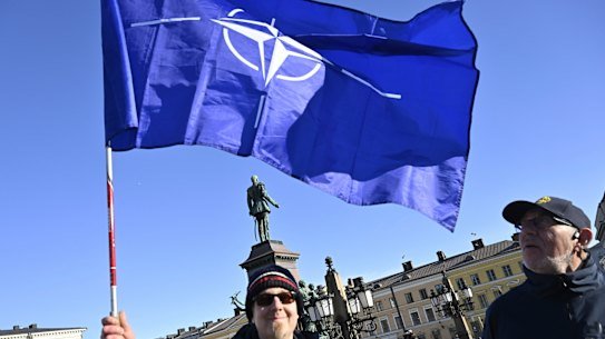 Two Finnish people with a NATO flag celebrate at the Senate Square in Helsinki, Finland.