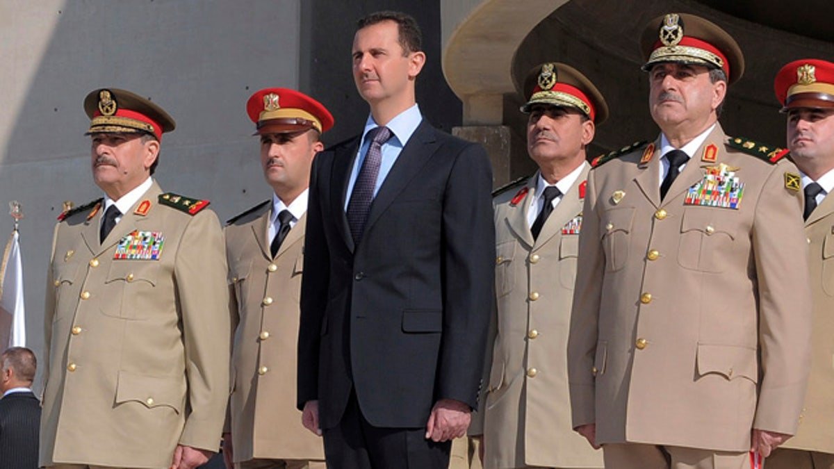 In this photo released by the Syrian official news agency SANA, Syrian President Bashar Assad, center, stands next to Syrian Defense Minister Gen. Dawoud Rajha, right, and Chief of Staff Gen. Fahed al-Jasem el-Freij, left, during a ceremony to mark the 38th anniversary of the October 1973 Arab-Israeli war, in Damascus, Syria, on Thursday Oct. 6, 2011. Syrian troops stormed villages close to the border with Turkey on Thursday, hunting armed military defectors who fought back in clashes that left at least four soldiers and three others dead, activists said. (AP Photo/SANA) EDITORIAL USE ONLY