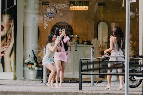 Women pose for social media photographs on Cross Street.