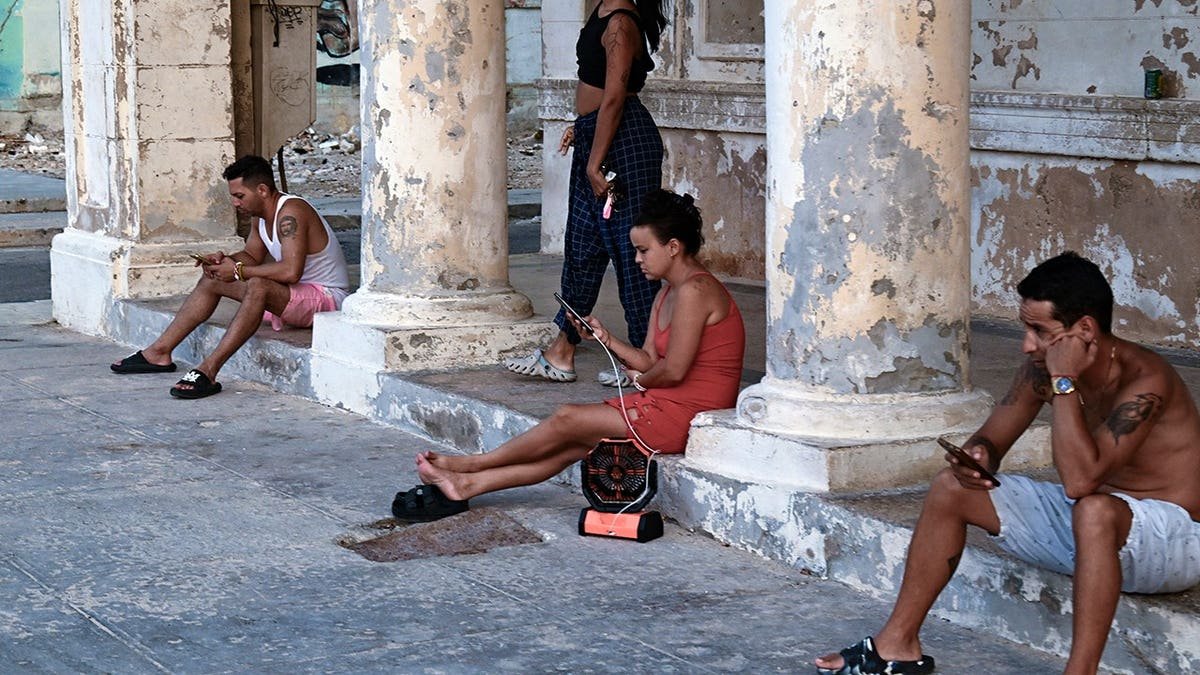 View of Cubans sitting on street during blackout crisis