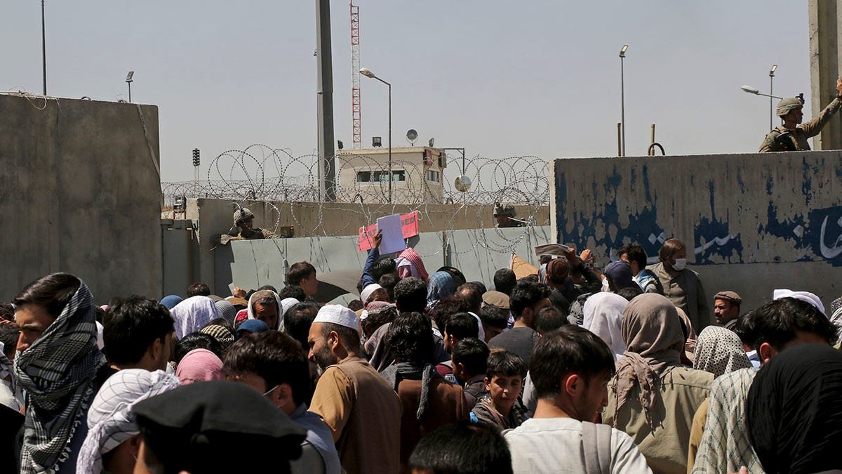 U.S. soldiers stand inside the airport wall as hundreds of people gather near an evacuation control checkpoint on the perimeter of the Hamid Karzai International Airport, in Kabul, Afghanistan, Thursday, Aug. 26, 2021. Western nations warned Thursday of a possible attack on Kabul's airport, where thousands have flocked as they try to flee Taliban-controlled Afghanistan in the waning days of a massive airlift. Britain said an attack could come within hours. (AP Photo/Wali Sabawoon)