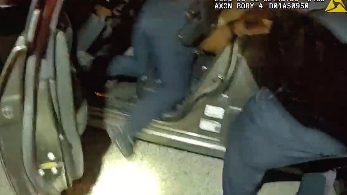 image shows officer's leg sticking out of driver's side door frame to vehicle.