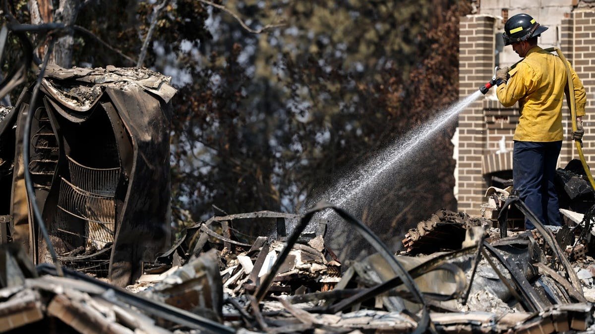 Firefighter extinguishing hotspots in Spokane, Washington.