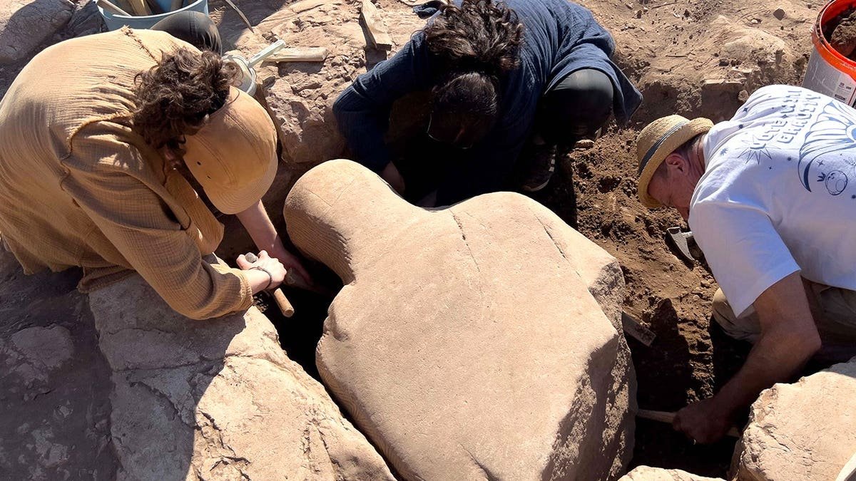 Archaeologists extracting ancient statue at site