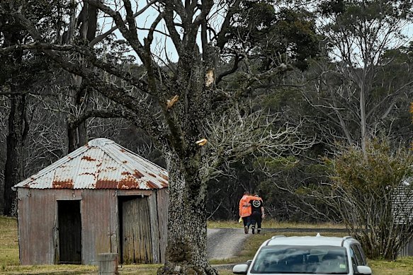 Jim Hooper (left, in orange), the father of missing bushwalker Lily Hooper, walks towards the search area where his daughter’s body was located on Thursday.