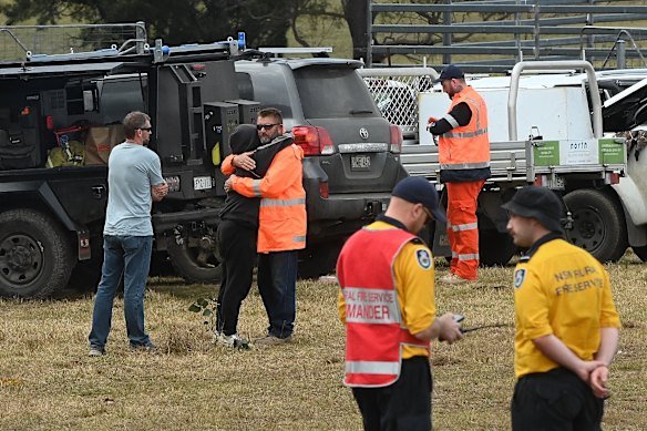 Lily’s father Jim, wearing an orange high-vis jacket, is embraced at the command post on Thursday.