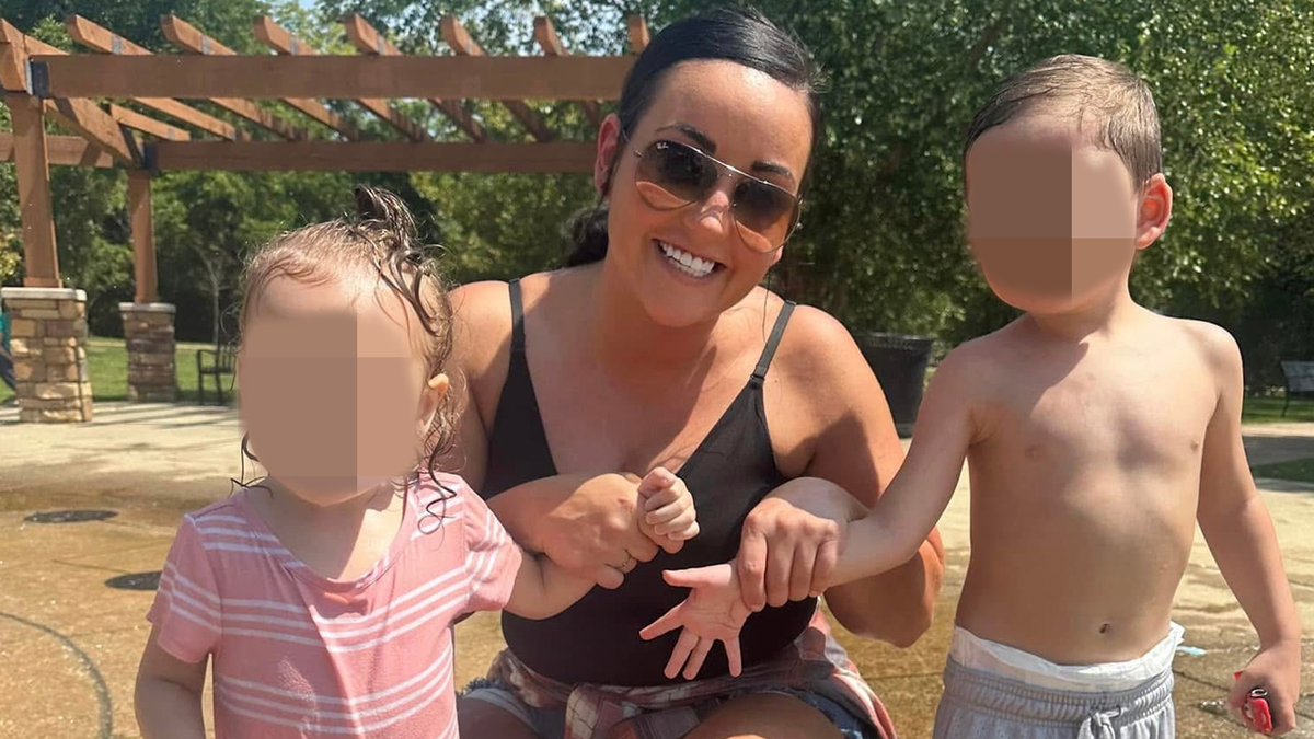 Bridget Reagan smiles while posing outdoors with two children