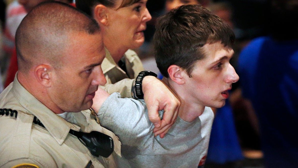 FILE - In this June 18, 2016, photo, police remove Michael Sandford as then Republican presidential candidate Donald Trump speaks at the Treasure Island hotel and casino in Las Vegas. Officials say Sandford has been deported after nearly 11 months in U.S. custody for trying to grab a police officer's gun in a bid to kill Trump at a campaign rally. An Immigration and Customs Enforcement spokeswoman said Sandford was escorted Wednesday, May 3, 2017, by federal agents aboard a commercial aircraft for his flight home to England. (AP Photo/John Locher, File)